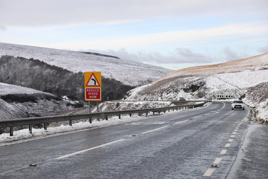 A car drives past a landscape covered in snow near Penistone, as freezing conditions grip Northern England during a cold snap