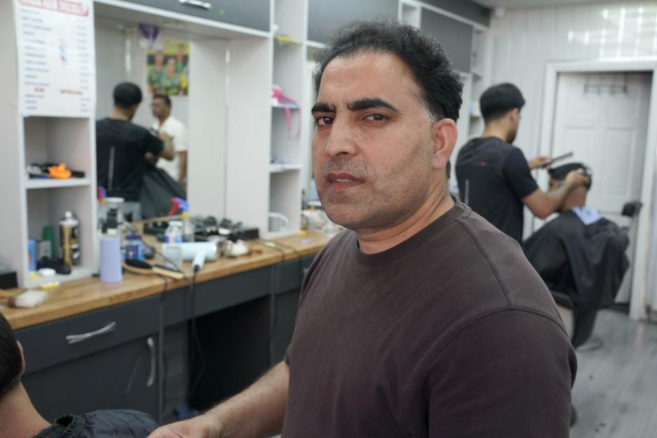 Hairdresser Imran Khan looking at the camera from his salon.