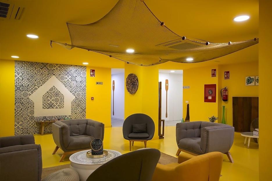 Lobby of Casual del Mar Málaga hotel in Spain with yellow walls and seating areas.