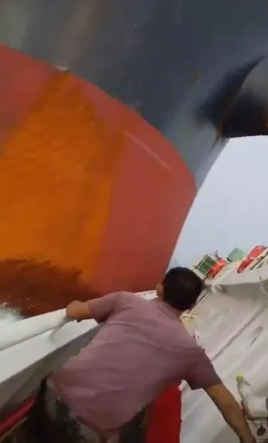 Terrifying moment gigantic ship crashes into fishing boat as water submerges vessel and crew desperately cling on
