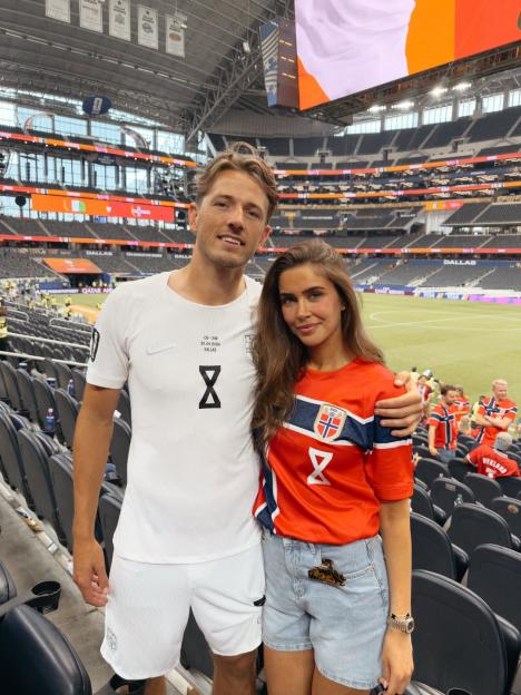 A man and a woman in soccer jerseys posing for a photo in a stadium.