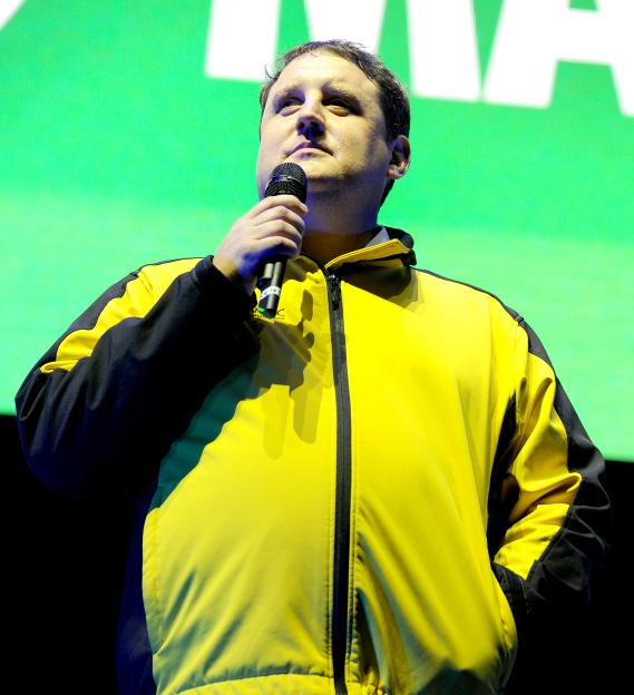 Peter Kay in a yellow and black jacket, giving a speech at the We Are Manchester benefit concert.
