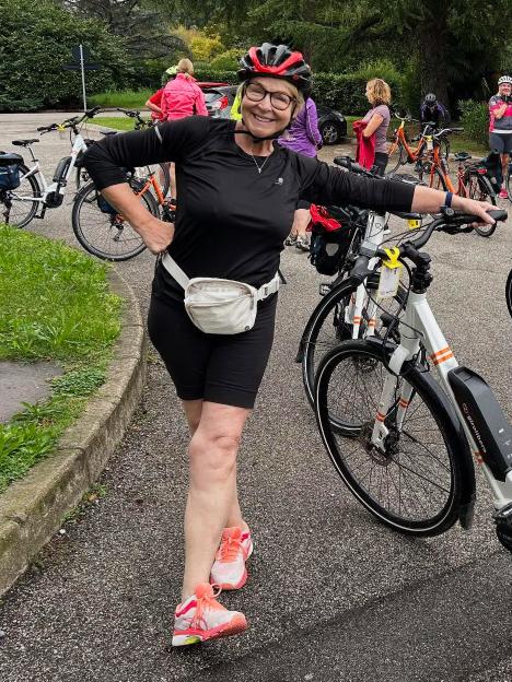 Fern Britton, in cycling shorts and helmet, smiles next to her bicycle.