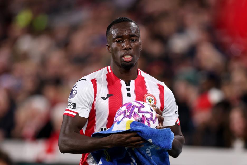 Michael Kayode of Brentford dries the ball with a towel during a soccer match.