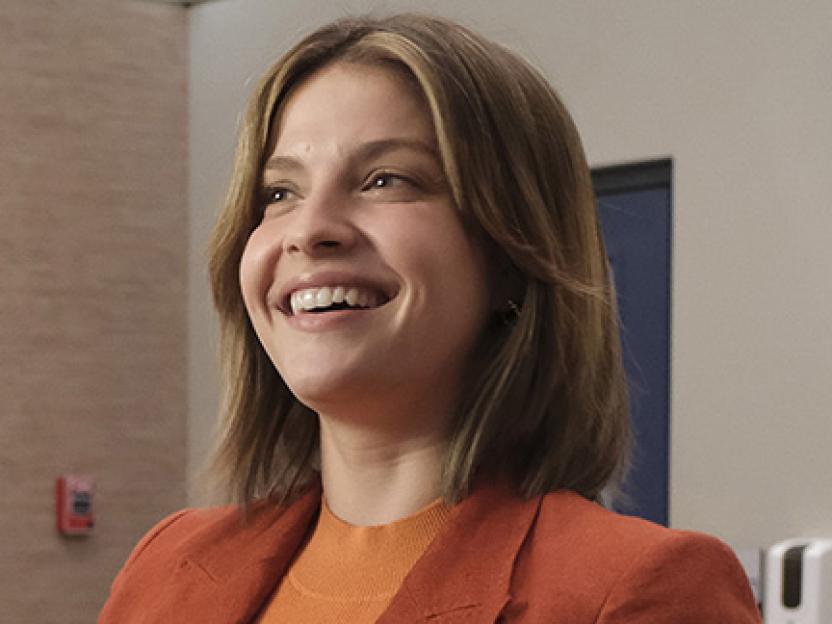 Paige Spara as Leah, smiling broadly.