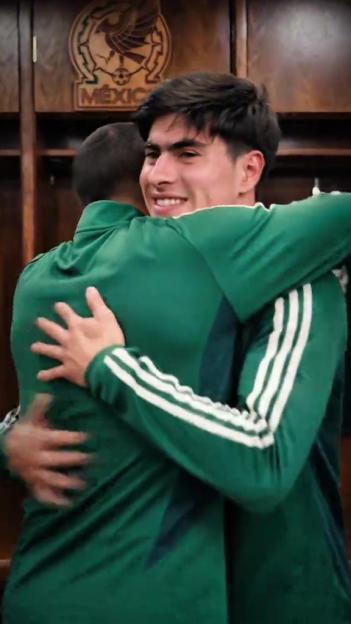 Two men in green tracksuits embracing, with a Mexico soccer emblem visible in the background.