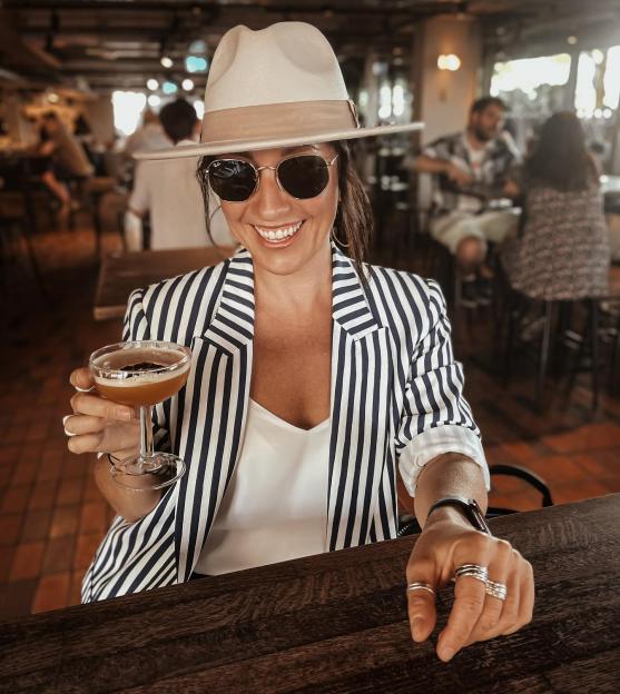 a woman in a striped jacket is holding a martini