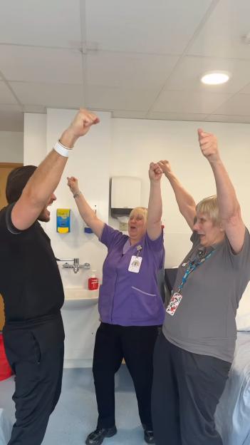 Jordan Brook and two nurses raise their arms in celebration of his hospital discharge.