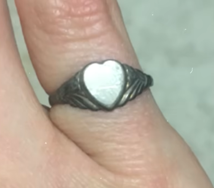 A ring with a heart-shaped top on a finger.