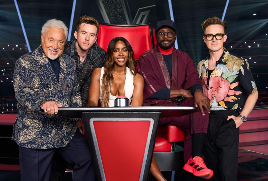 The coaches of The Voice UK, Sir Tom Jones, Tom Fletcher, Kelly Rowland, will.i.am, and Danny Jones, pose on set.