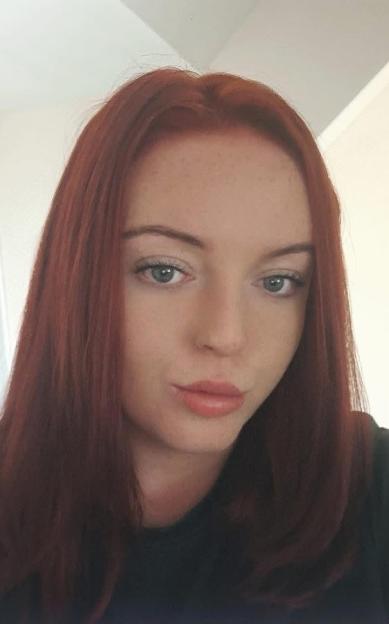 Headshot of Alexandra Walker, a woman with long red hair, blue eyes, and light pink lipstick.