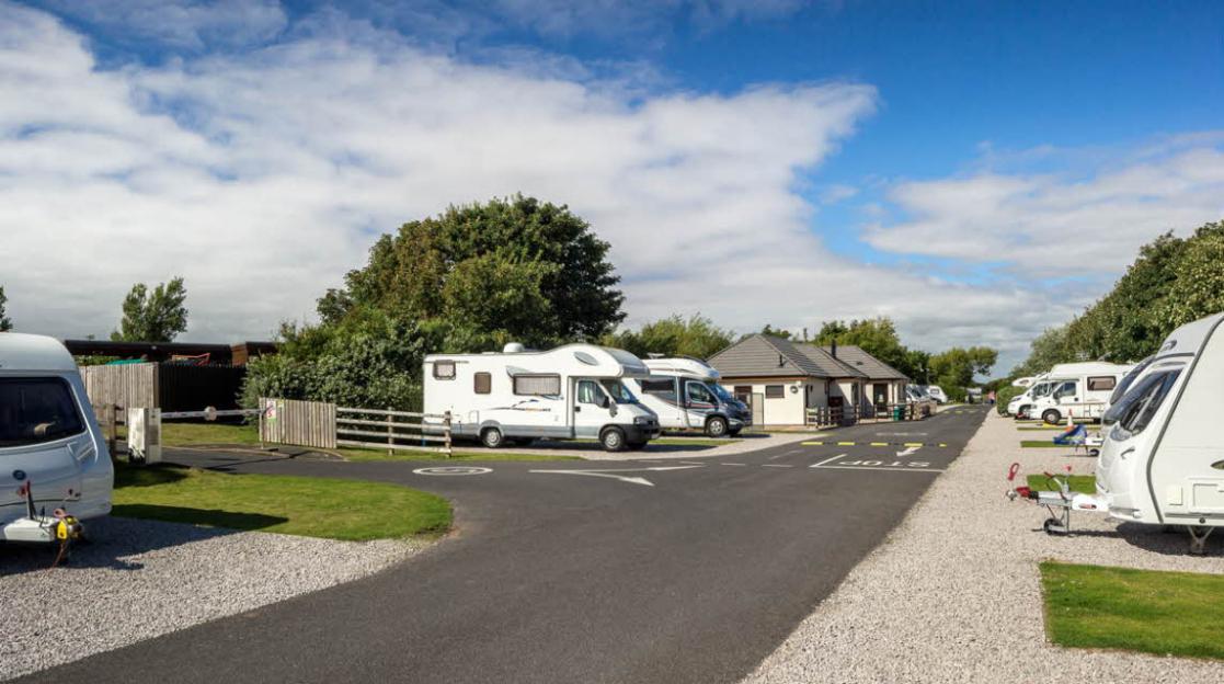 The Southport Club Campsite with caravans and RVs parked along a paved road.