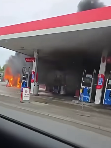 A campervan engulfed in flames at a petrol station forecourt.