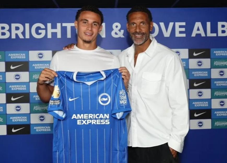 New Brighton & Hove Albion signee holding up his team jersey, posing with a man in a white shirt.