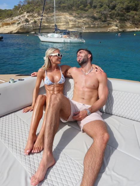 A man and woman relaxing on a boat in a sunny bay.