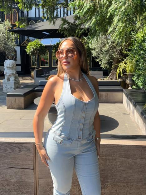 Sophie Kasaei wearing a denim jumpsuit and sunglasses outdoors.