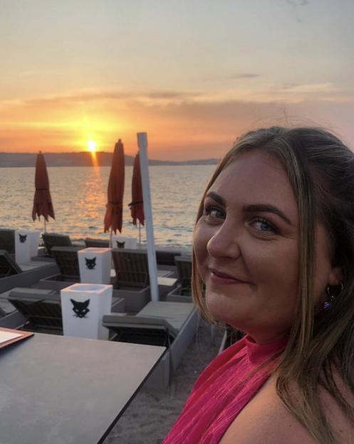 Clair Norris posing for a photo on a beach at sunset.