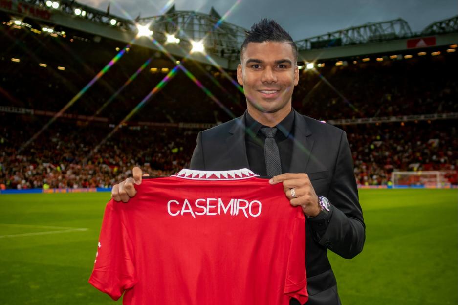 Casemiro holds up a Manchester United jersey with his name on the back.
