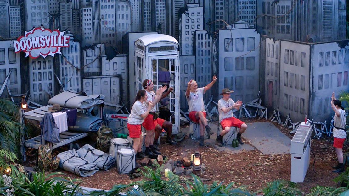 Campmates from 'I'm a Celebrity... Get Me Out of Here!' cheer and clap in a "Doomsville" set resembling a damaged city.