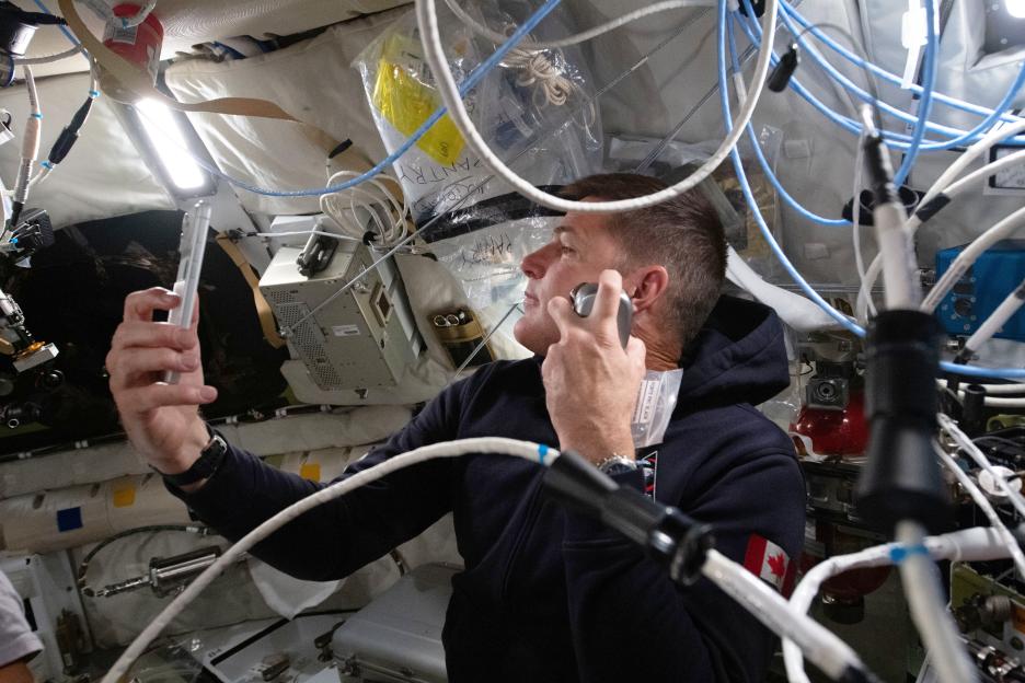 Astronaut Jeremy Hansen shaving inside the Orion spacecraft during the Artemis II mission.