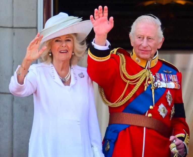 Queen Camilla and King Charles III waving.