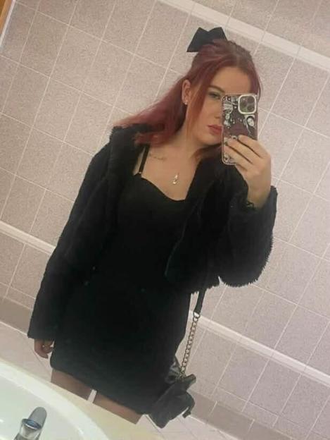 Keeleigh, a young woman with auburn hair, taking a selfie in a mirror.