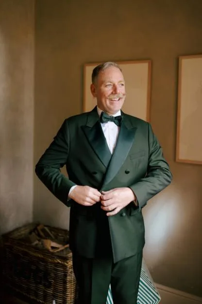 Rufus Hound wearing a dark green tuxedo with a bow tie.