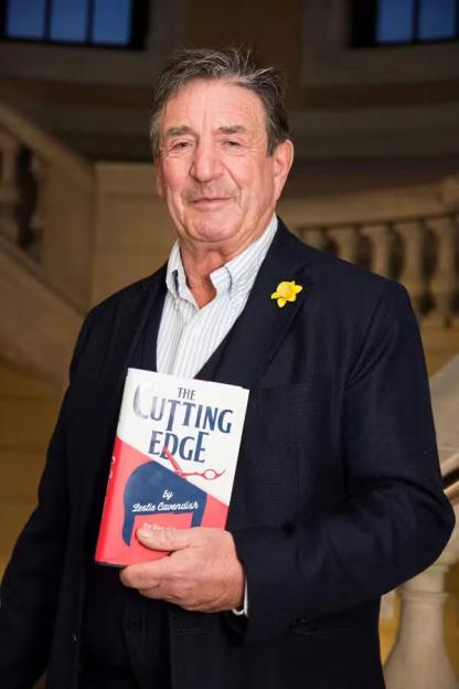 Leslie Cavendish holding his book, "The Cutting Edge".