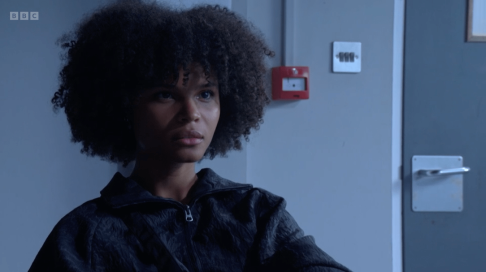 A young woman with curly hair wearing a black jacket.