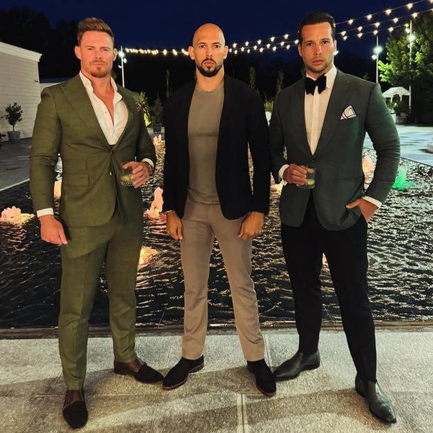 Andrew Tate, Tristan Tate, and Justin Waller standing in front of a fountain at night.