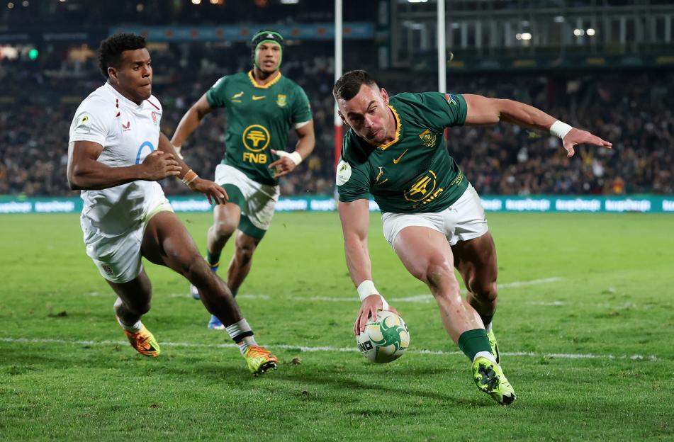 Jesse Kriel of South Africa scores a try while under pressure from Immanuel Feyi-Waboso of England during a rugby match.