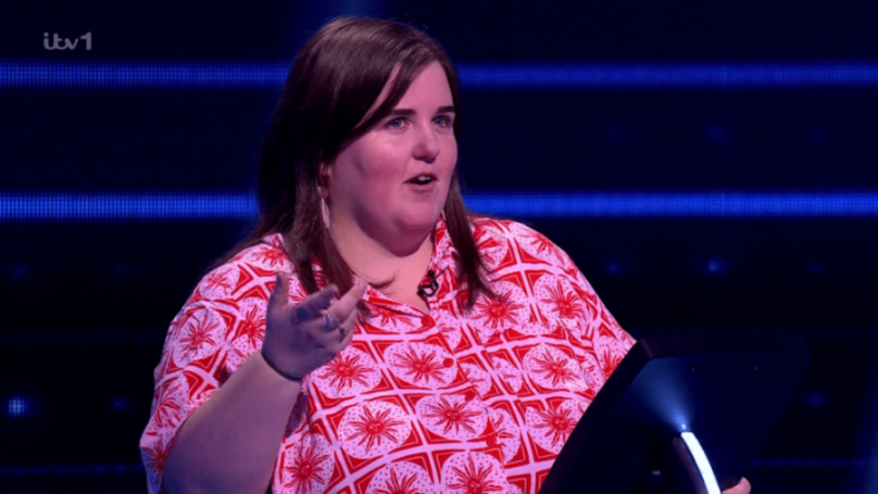 A woman in a red and white patterned shirt speaking on a game show.