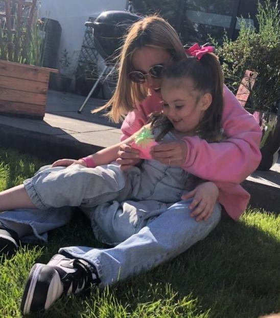 Kaylie Kelliher, 37, and her 7-year-old daughter, Boe Bushnell, sitting on the grass.