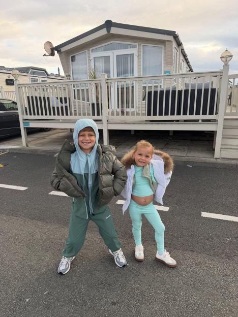 Ronnie Foden and a young girl posing in front of a holiday park caravan.