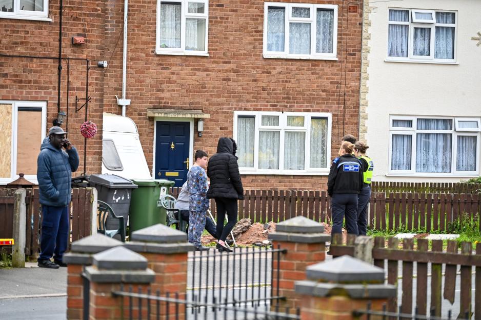 Police and residents standing outside a row of houses.