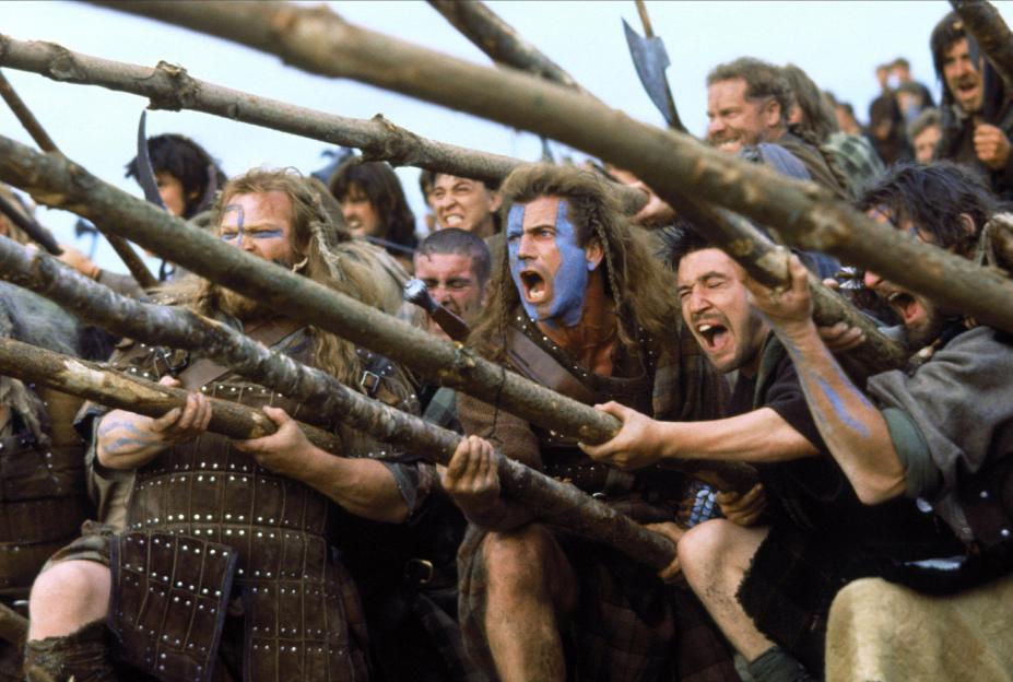 Mel Gibson as William Wallace and other warriors with painted faces holding long wooden poles in Braveheart.