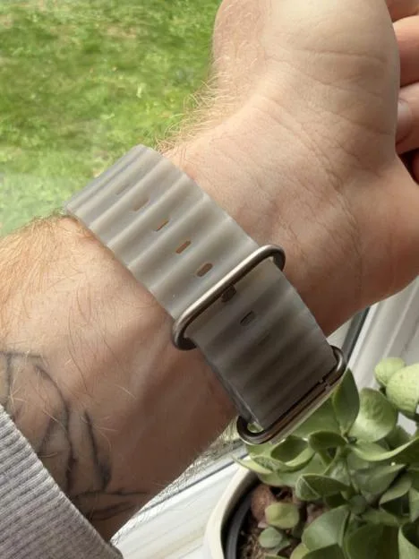 Close-up view of the underside of a wrist wearing a ridged, translucent grey watch band with a metal buckle.