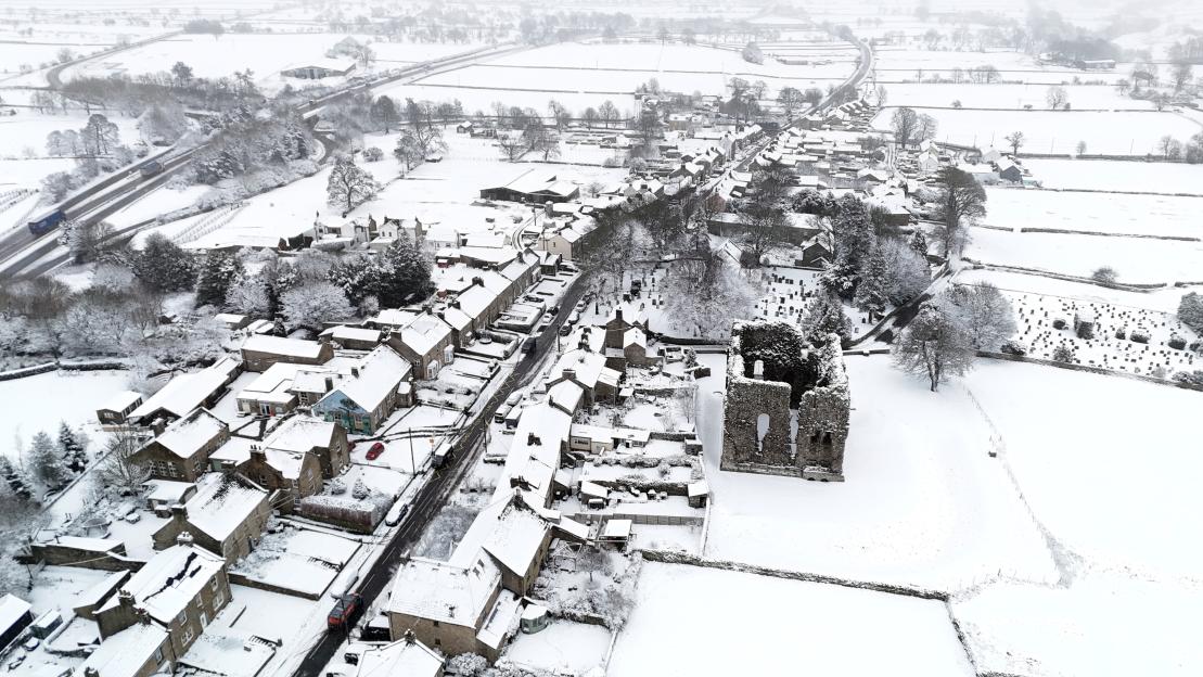 Aerial view of Bowes Castle and village in County Durham covered in snow and ice.