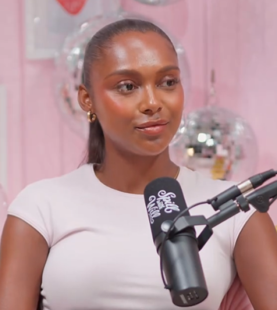 A woman in a white t-shirt and a microphone in front of her.