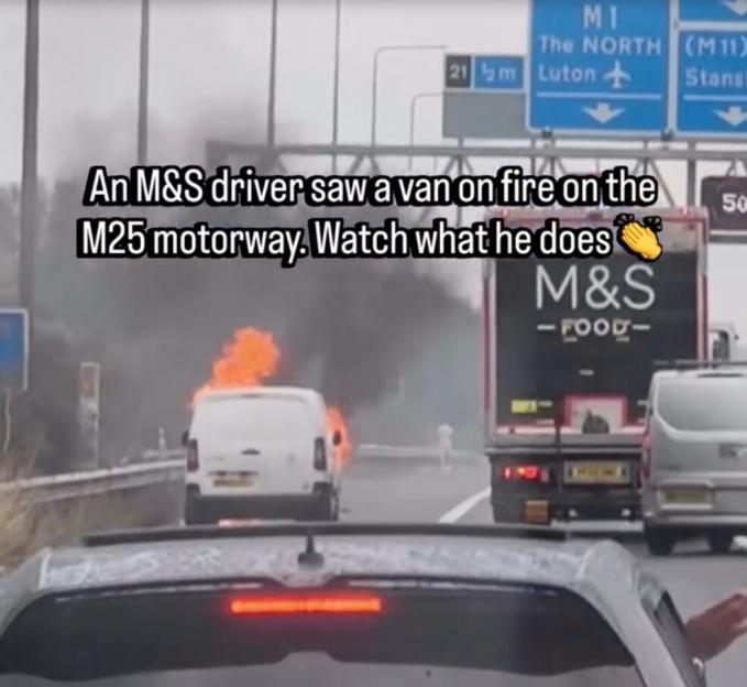 A white van burning on the M25 motorway, with an M&S food truck stopped behind it and a grey car in the foreground.