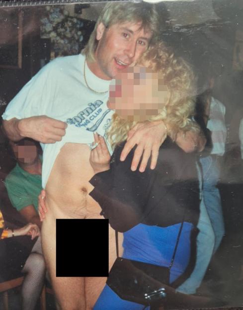 Jon Worboys, a man with a mullet, standing shirtless while holding a woman.