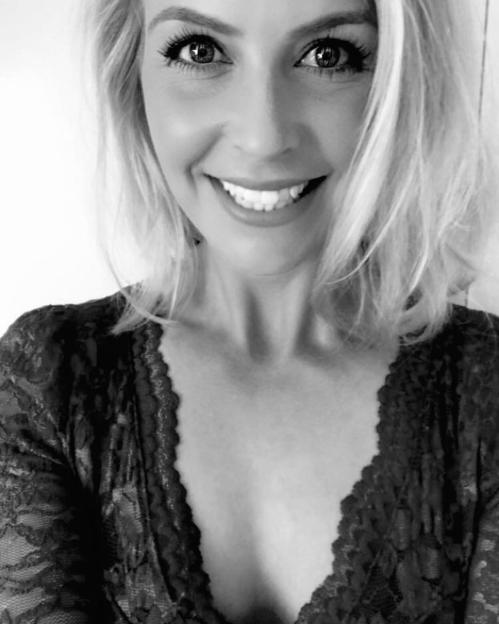 Black and white close-up of a smiling blonde woman in a lace top.