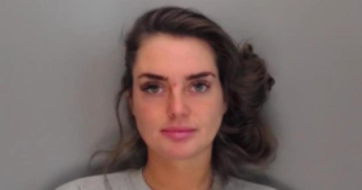 Mugshot of a woman with dark hair pulled to one side, looking straight ahead.