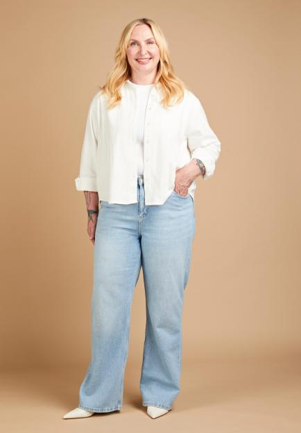 Annikki Sommerville wearing light wash wide-leg jeans, a white t-shirt, and a white button-up shirt.