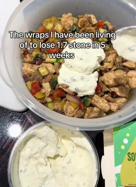 A bowl of seasoned chicken, bell peppers, and zucchini with a scoop of white sauce, and a container of sauce on the side.