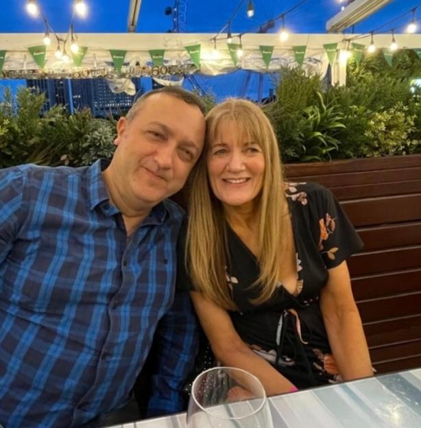 John and Gilly smile for a photo with the London Eye in the background at night.
