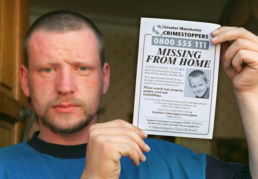 Bus driver Darren Vickers holds a "Missing From Home" poster for James Lavis, the schoolboy he was found guilty of murdering.