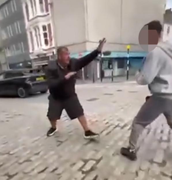 Serial killer James Desborough sparring with a teenager on a cobbled street.