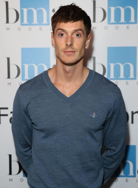 A man in a blue V-neck sweater stands in front of a white background with a "bm MODEL" logo.