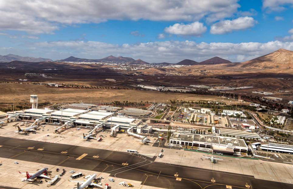 Aerial view of Lanzarote Airport in the Canary Islands, Spain, with airplanes on the tarmac and mountains in the background.